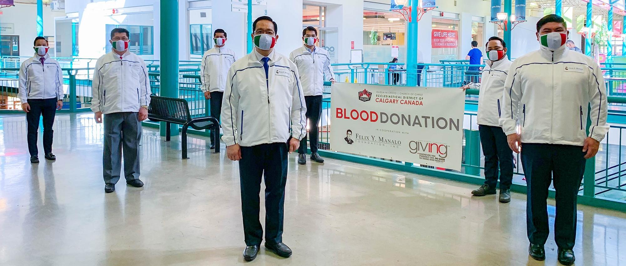 Members of Iglesia ni Cristo (Church of Christ) stand near a sign advertising a blood donation event in Calgary, Alta.