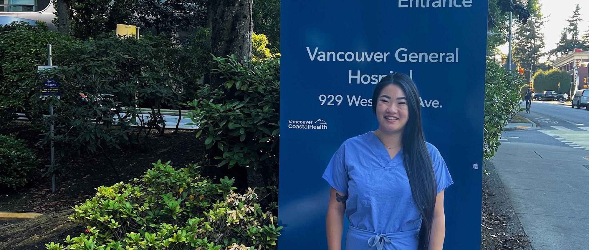 Nurse who is a living organ donor in front of hospital sign