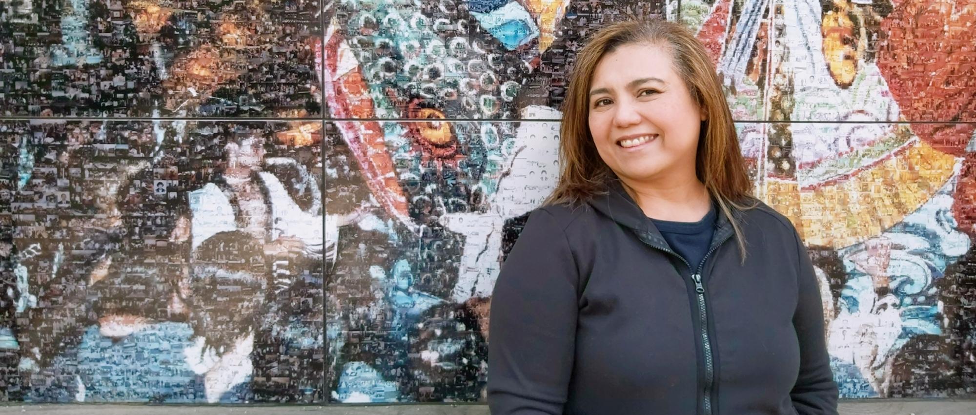 Lilet Raffiñan, a Canadian of Asian heritage who recruits donors for Canadian Blood Services, stands in front of a colourful mural.