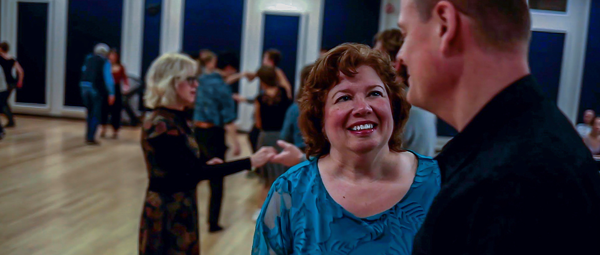 Image of Linda Paul dancing with a man in her dancing class with other couples dancing.