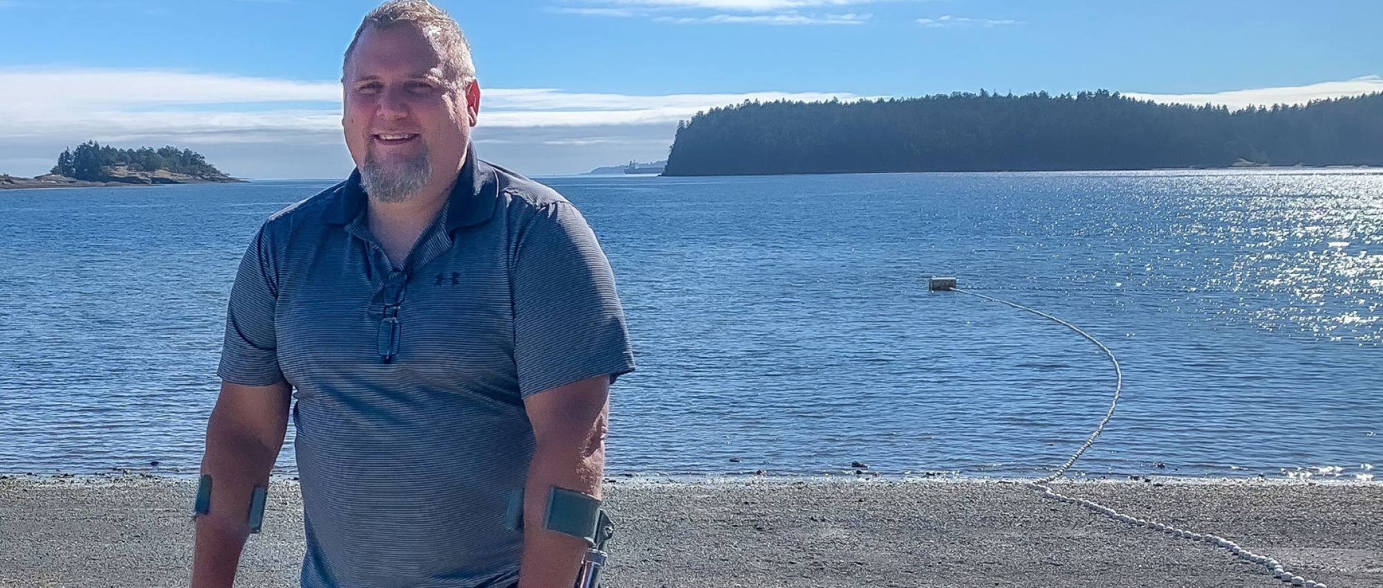 Featured image of blood recipient Nathan Olson from British Columbia standing in front of a beach holding crutches after the motorcycle accident