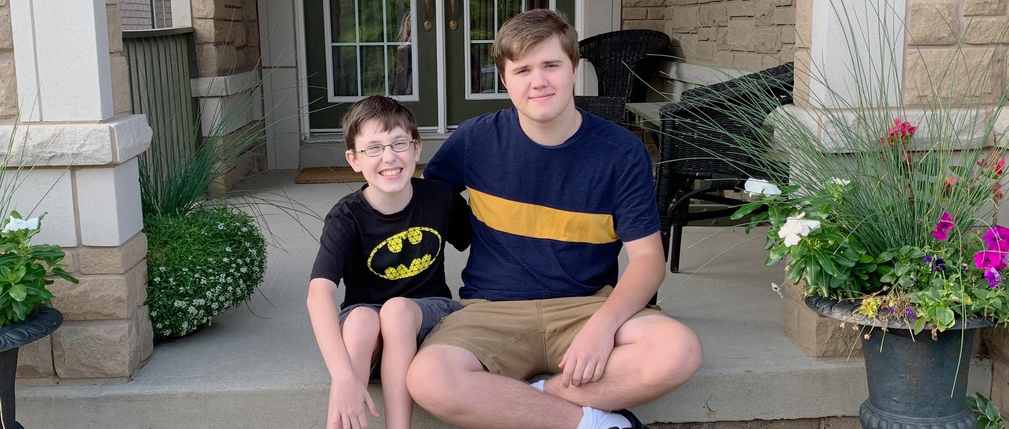 Nolan Clark, a teen who donated blood for the first time, sits on a porch with his younger brother Nicholas who had blood transfusions as an infant.