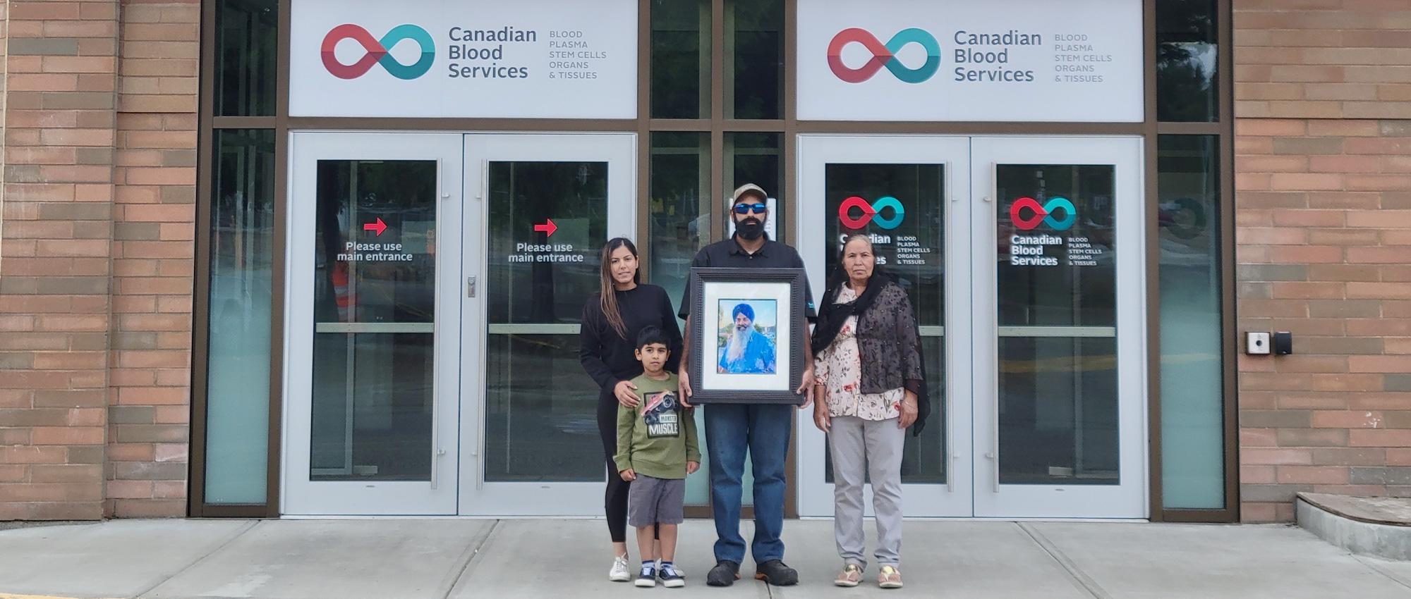 Bunvir Kaur and her family with a photo of her father outside the plasma donor centre in Kelowna, B.C.