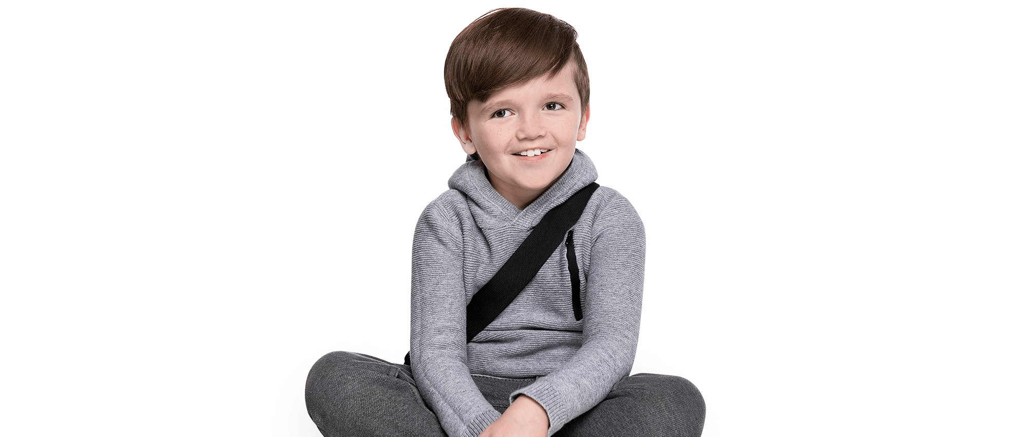 Young boy sits cross-legged, smiling