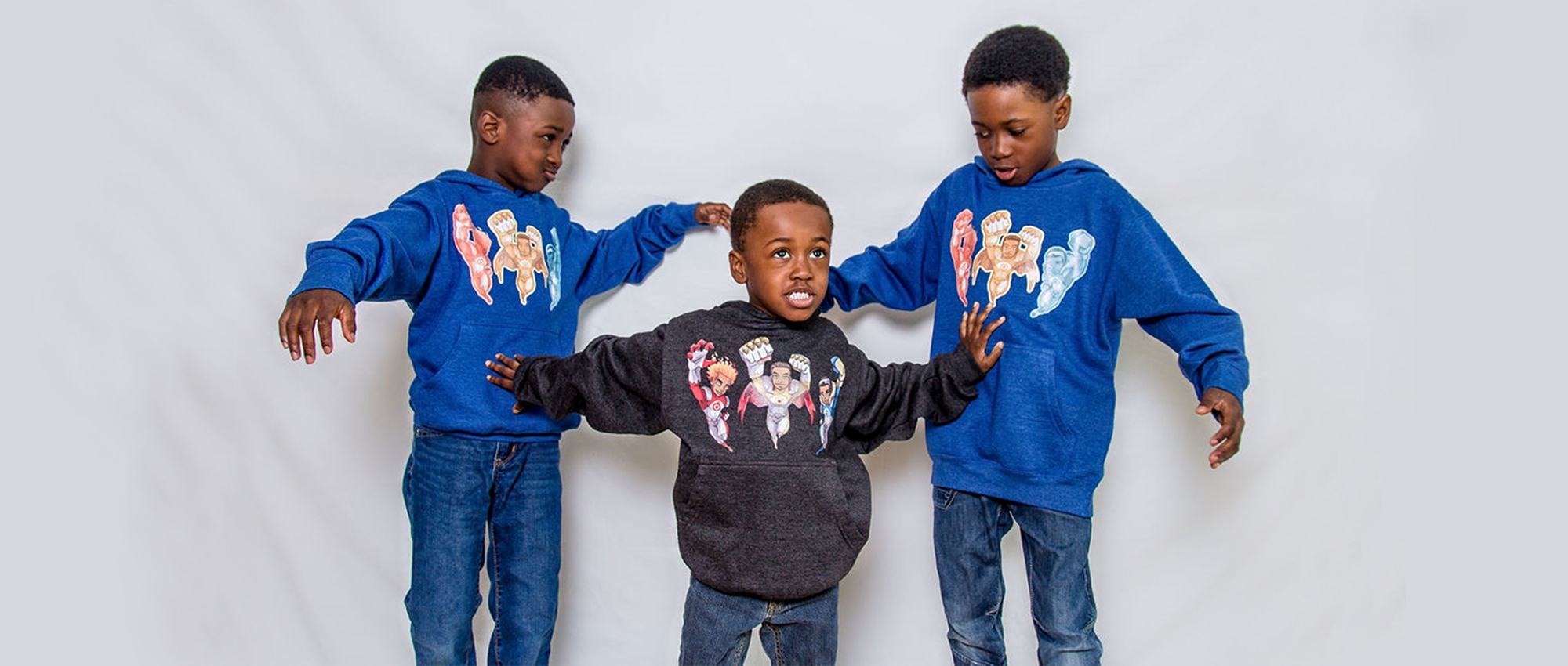 Hezekiah, Joiakim and Micah Felix pose in shirts that display the superhero characters in the book The Battle of Ottogatz. 