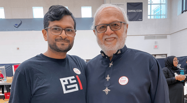 Father and son wearing “proud donor” stickers at blood donation event 