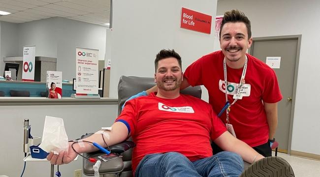 Man donating blood with partner smiling at his side