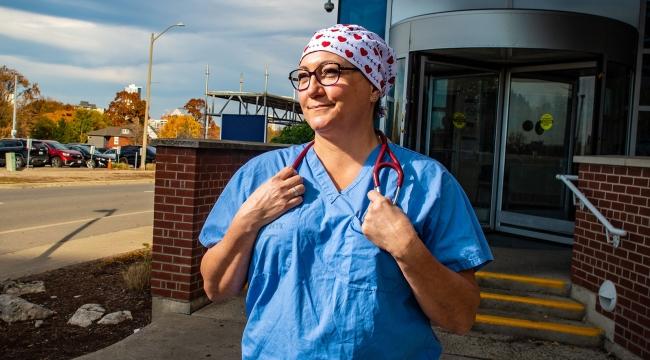 Une infirmière de salle d’urgence pose en tenue de travail à l’extérieur d’un hôpital