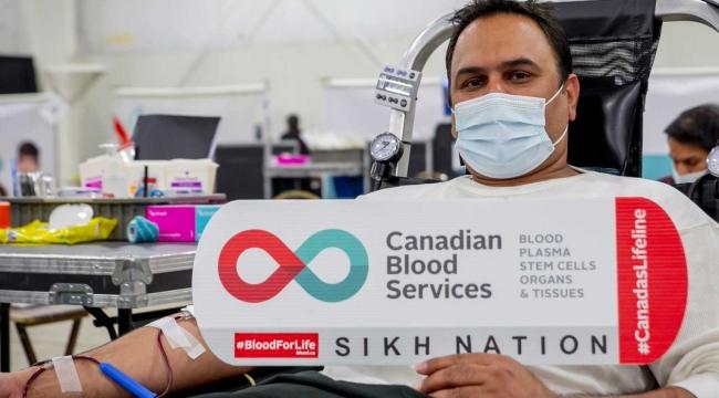 A man donating blood holding a sign that says Sikh Nation