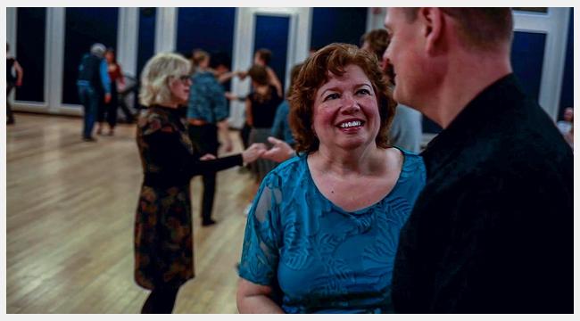 Image of Linda Paul dancing with a man in her dancing class with other couples dancing.