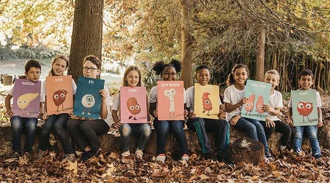 Nine children in a forest each with poster of an Orgamites figure