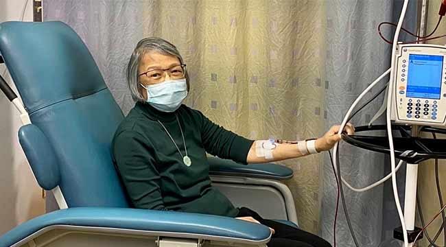 A woman in a mask receiving a blood transfusion