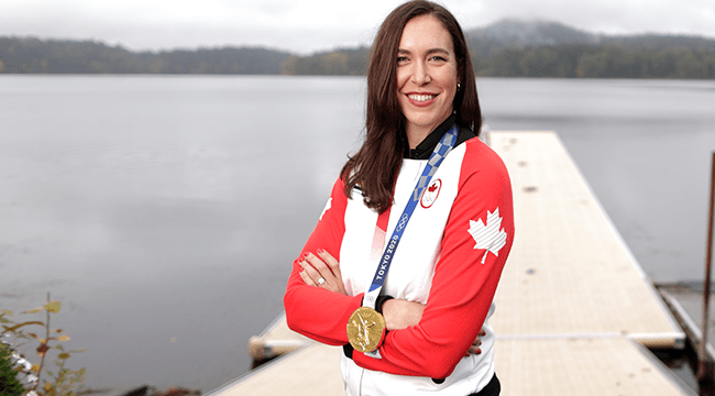 Andrea Proske wears Olympic gold medal near lake and trees 