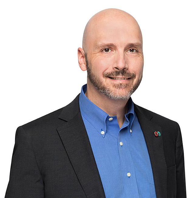 Image of director of plasma protein products formulary Dr. Sylvain Grenier wearing a blue dress shirt and a black blazer.