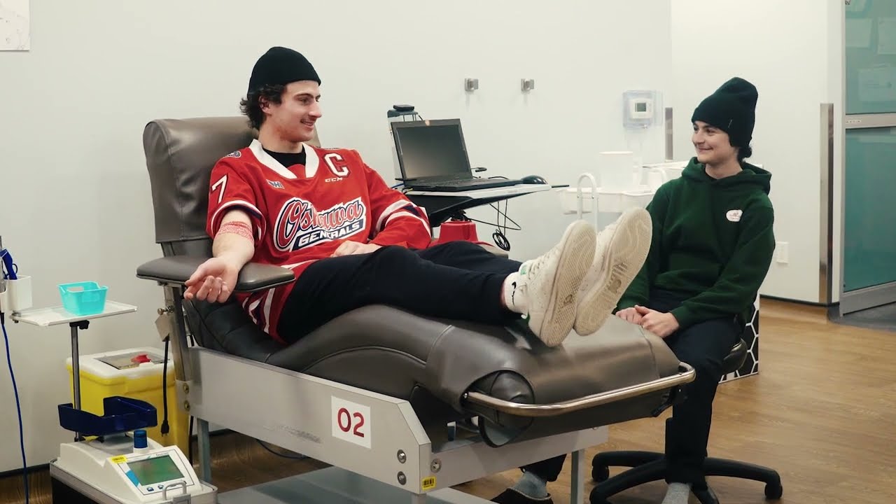 Ben Danford wearing a red jersey donating blood in a donation bed
